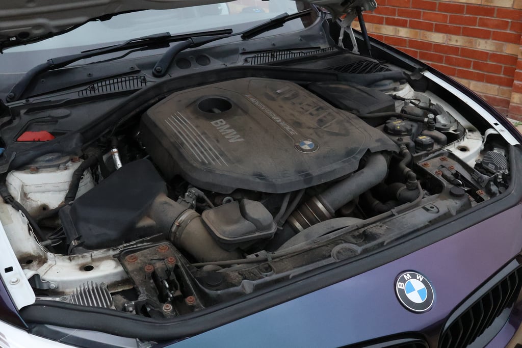 BMW engine cover before cleaning, grey with baked-on dust