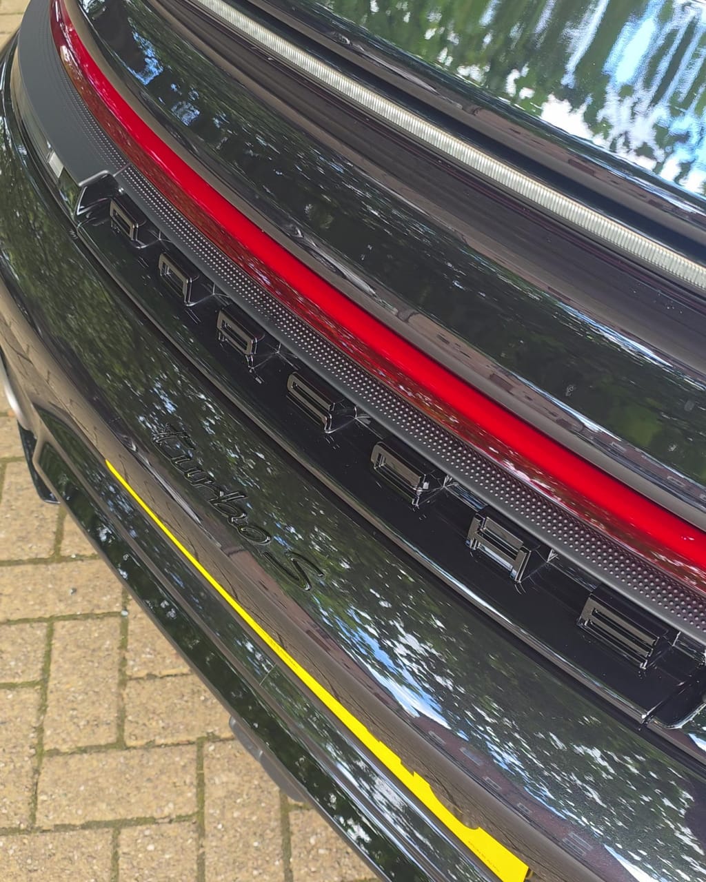 The same Porsche rear bumper after the valet, PORSCHE lettering crisp and the diffuser vents clear
