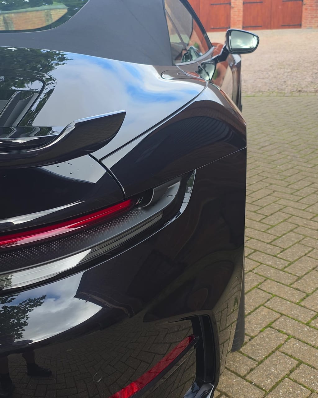 The same rear quarter panel after the valet, the block paving mirrored cleanly in the paint