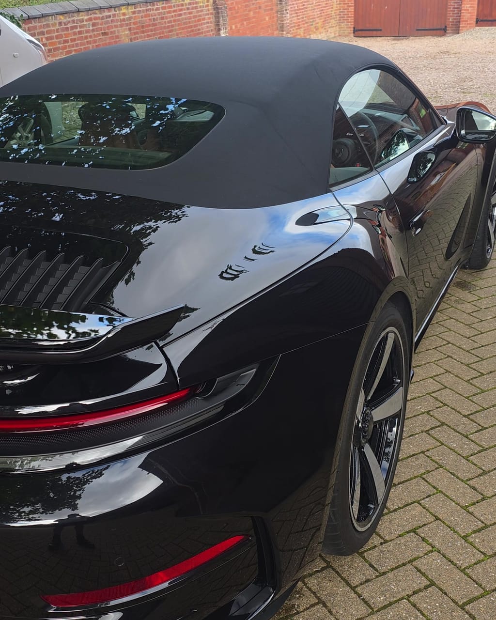 Rear three-quarter of the same Porsche after the valet, engine lid and haunch holding a clean reflection