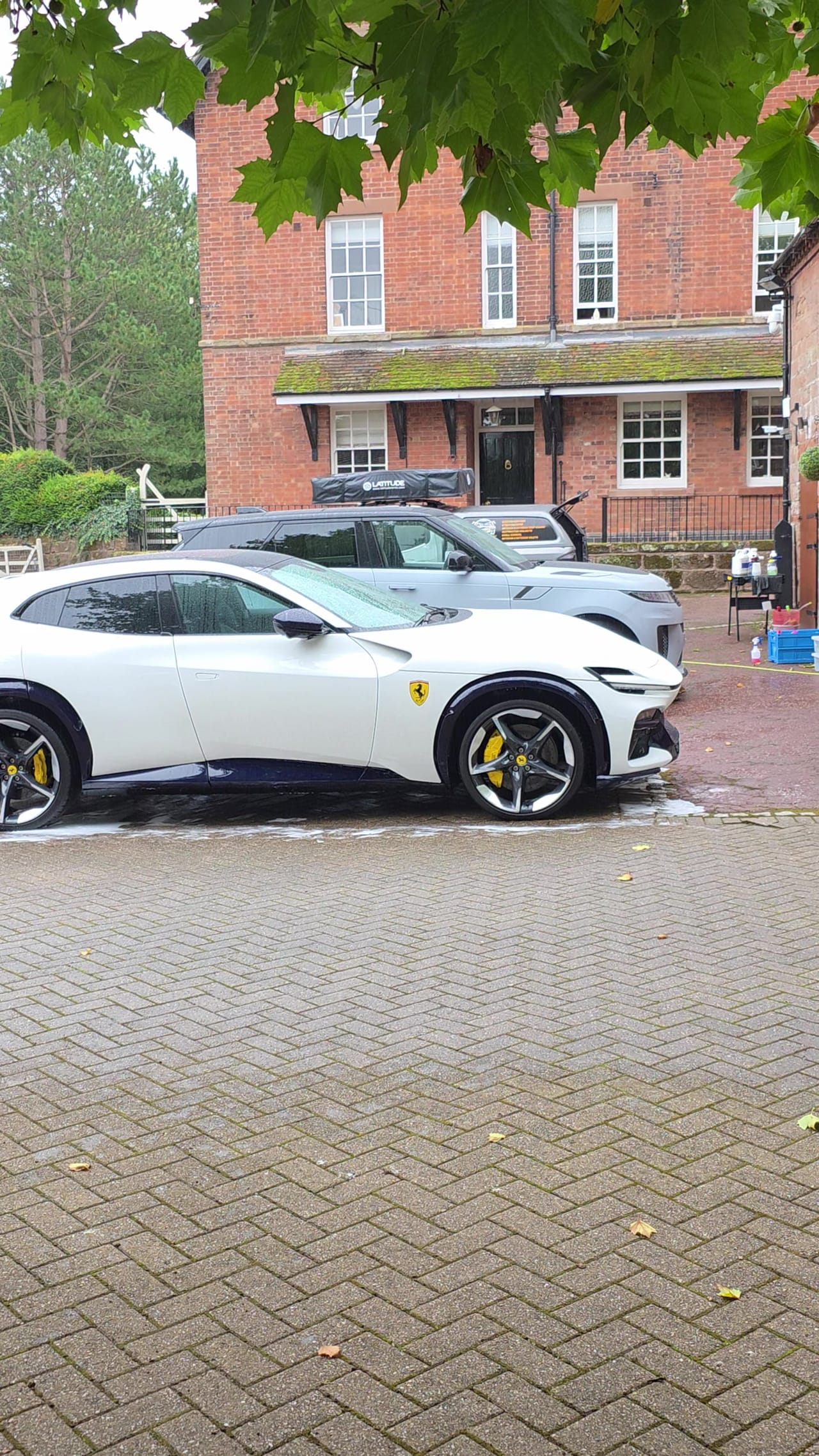 White Ferrari Purosangue after a maintenance valet, parked on a block-paved driveway