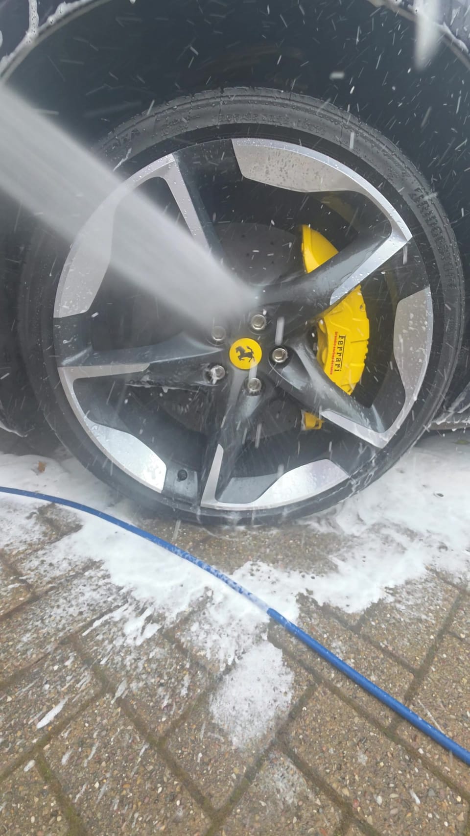 Purosangue forged wheel and yellow Ferrari caliper being rinsed after a pH-neutral clean