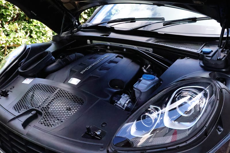Porsche engine bay cleaned and dressed, bonnet raised on a driveway