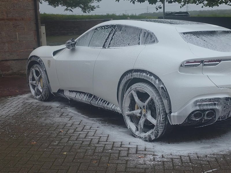 Rear quarter panel covered in snow foam before the contact wash