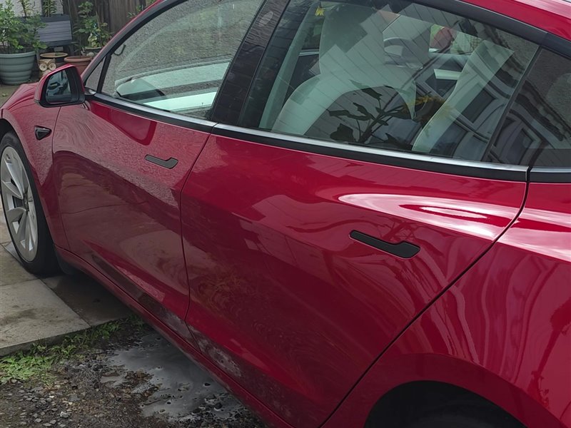 Red Tesla Model 3 side view after a maintenance valet